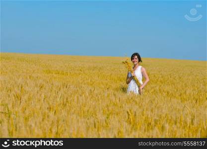 Young woman standing jumping and running on a wheat field with blue sky the background at summer day representing healthy life and agriculture concept