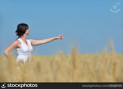 Young woman standing jumping and running on a wheat field with blue sky the background at summer day representing healthy life and agriculture concept