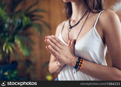 Young woman standing, meditate while practicing Yoga with hands in prayer position. Namaste Gesture