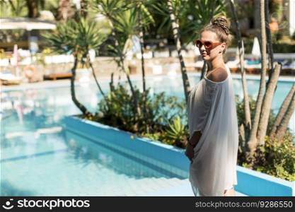 Young woman standing next to the pool and enjoying the sun