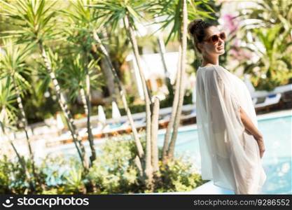 Young woman standing next to the pool and enjoying the sun