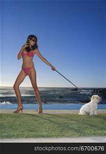 Young woman standing on a lawn holding a dog&acute;s leash