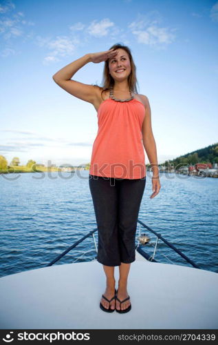 Young woman standing on a ship&acute;s bow and saluting