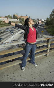 Young woman standing on an overpass with her arms outstretched