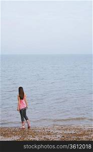 Young woman standing on beach, back view