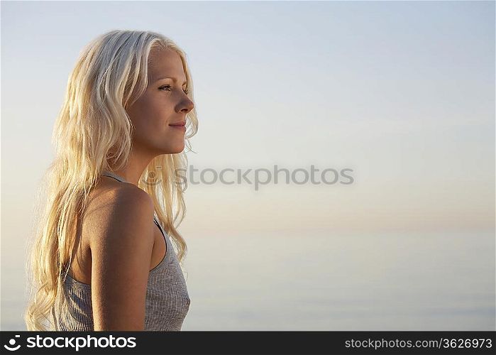 Young woman standing on beach, side view