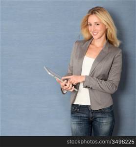 Young woman standing on grey background with touchpad