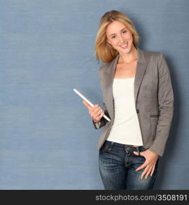 Young woman standing on grey background with touchpad