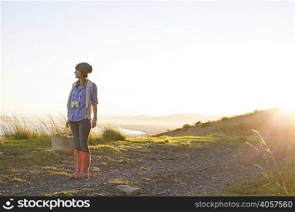 Young woman standing on hill at sunset