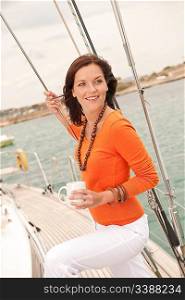 Young woman standing on sailing boat with cup of coffee on the sea
