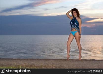 Young woman standing on the bay at sunset