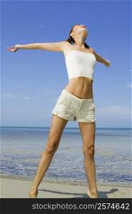 Young woman standing on the beach with her arms outstretched