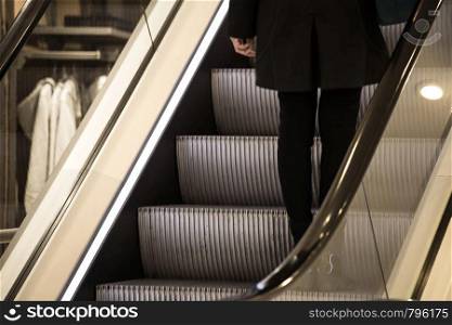 Young woman standing on the escalator in a shop close-up. Young woman standing on the escalator in a shop