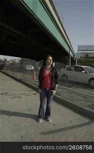 Young woman standing under an overpass with her hands in her pockets