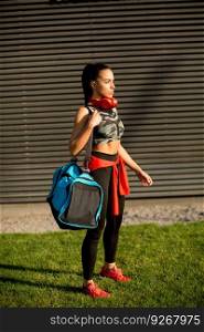 Young woman standing with sport bag outdoor