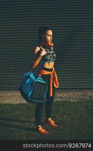 Young woman standing with sport bag outdoor after training