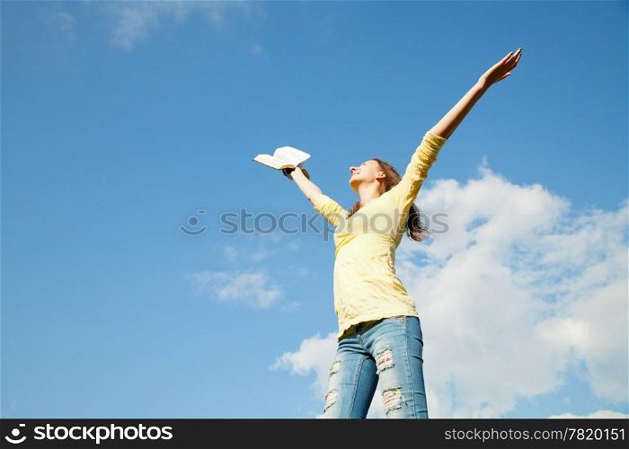 Young woman staying with raised hands against blue sky
