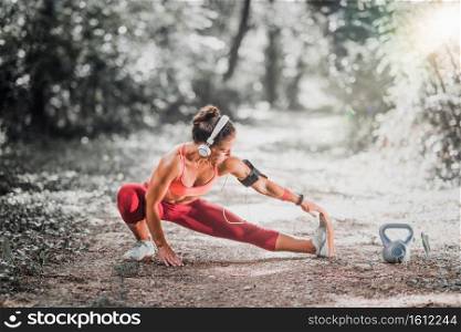 Young woman stratching after jogging in the park