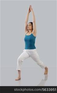 Young woman stretching arms upwards isolated over gray background