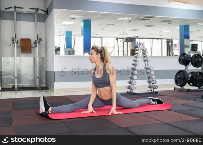 young woman stretching exercising indoors in fitness club. young woman stretching exercising in fitness club