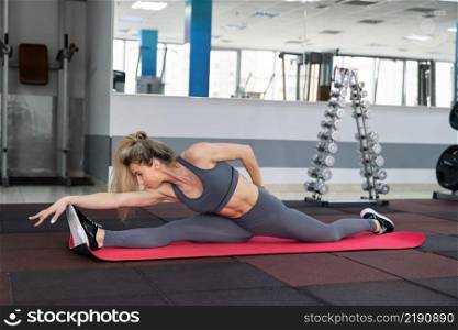 young woman stretching exercising indoors in fitness club. young woman stretching exercising in fitness club