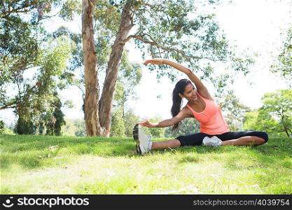 Young woman stretching in park