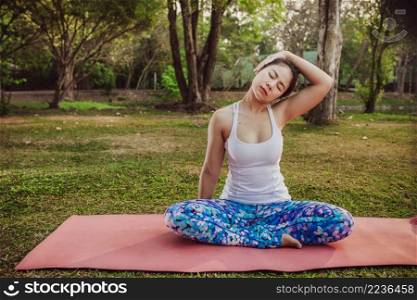 young woman stretching neck park
