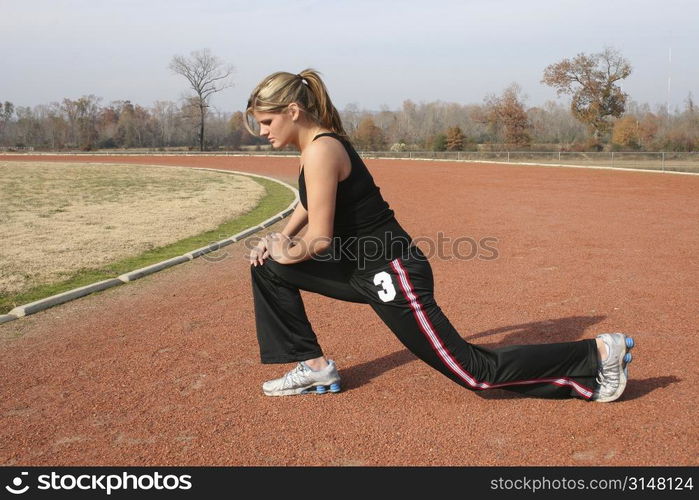 Young woman stretching outdoors at the track.