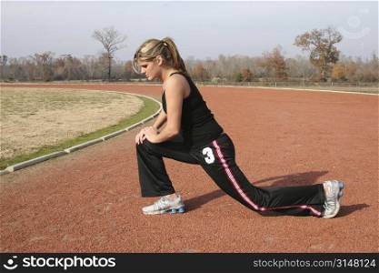 Young woman stretching outdoors at the track.