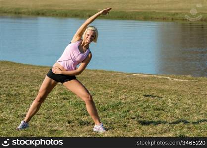 Young woman stretching outdoors before jogging workout sunny park