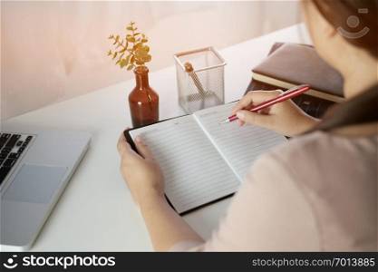 young woman studying while sitting at the table with laptop computer and notebook during lesson in classroom