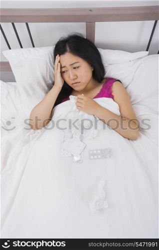 Young woman suffering from cold and headache lying in bed