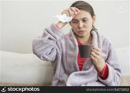 Young woman suffering from cold having coffee on bed