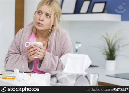 Young woman suffering from cold holding coffee mug