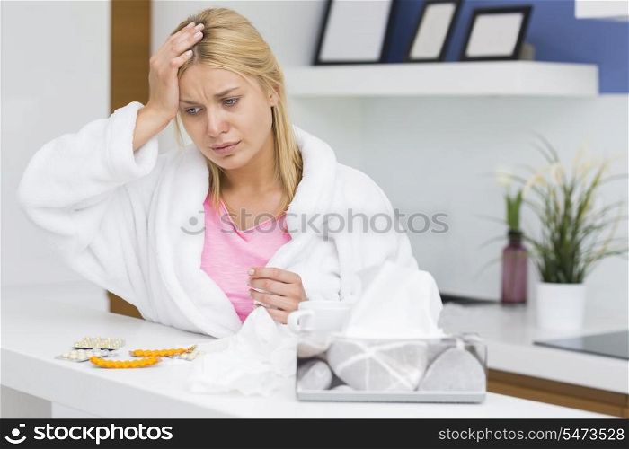 Young woman suffering from cold in kitchen