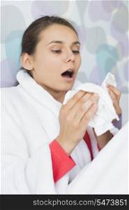 Young woman suffering from cold sneezing at home