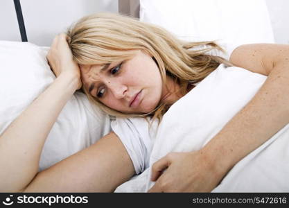 Young woman suffering from headache in bed