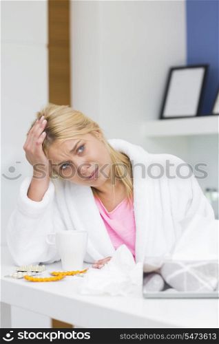 Young woman suffering from headache in kitchen