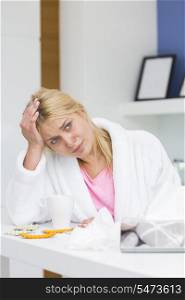 Young woman suffering from headache in kitchen