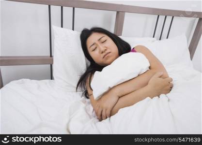 Young woman suffering from stomach ache lying in bed