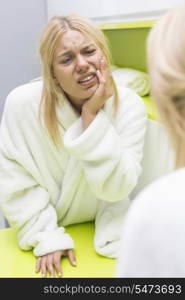 Young woman suffering from toothache while looking at mirror