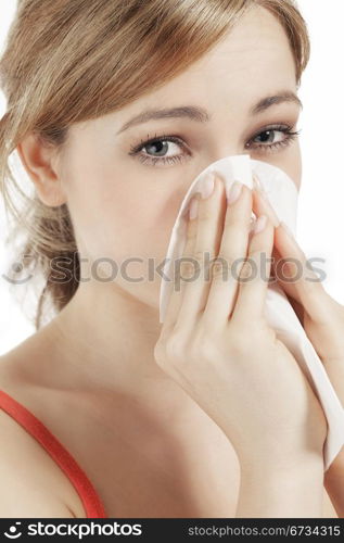 young woman suffering on hay fever. young blonde woman suffering on hay fever sneezing with a paper tissue