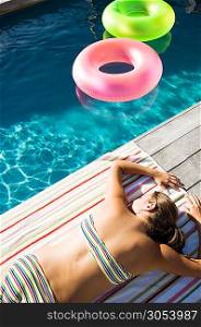 Young woman sunbathing at poolside