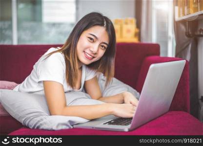Young woman surfing the internet by laptop on red sofa in cheerful gesture mood emotion. Selling and online shopping concept. Merchant and marketing. Happiness of new business trader and entrepreneur