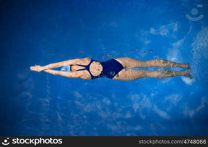 Young woman swimmer in blue pool water