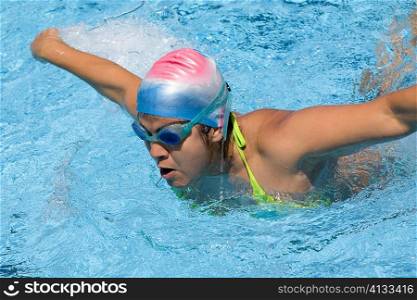 Young woman swimming the butterfly stroke in a swimming pool