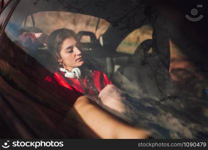 Young woman takes refuge inside a car while it rains on the field