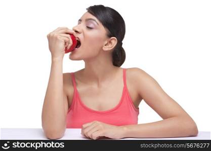 Young woman taking a bite of fully ripped apple over white background