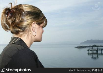 Young woman taking a break out by the lake. Casual business attiire. Looking out at water.