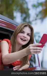 Young woman taking a picture with a mobile phone and laughing
